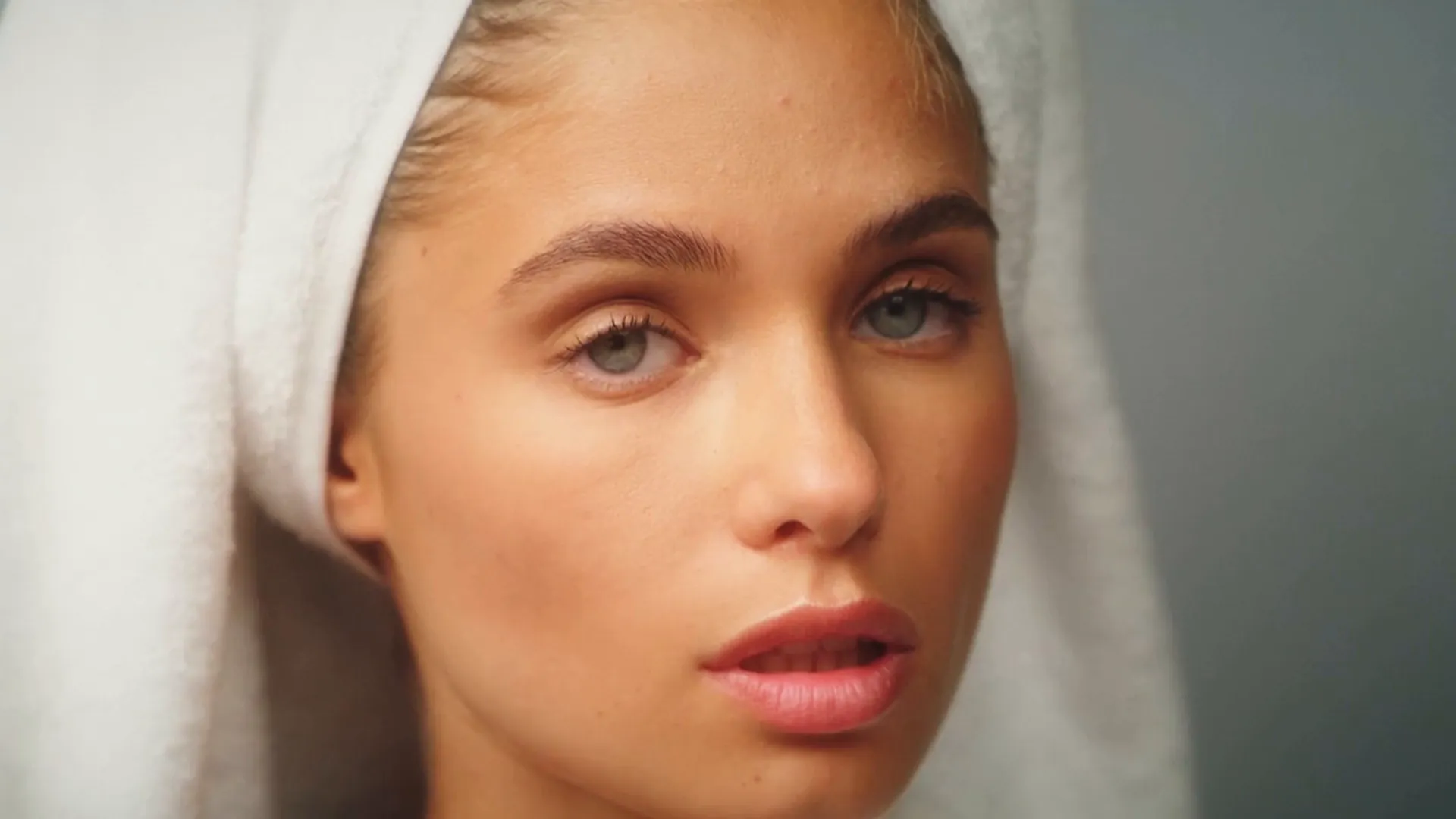 Gros plan sur le visage d’une jeune femme, une serviette blanche sur les cheveux