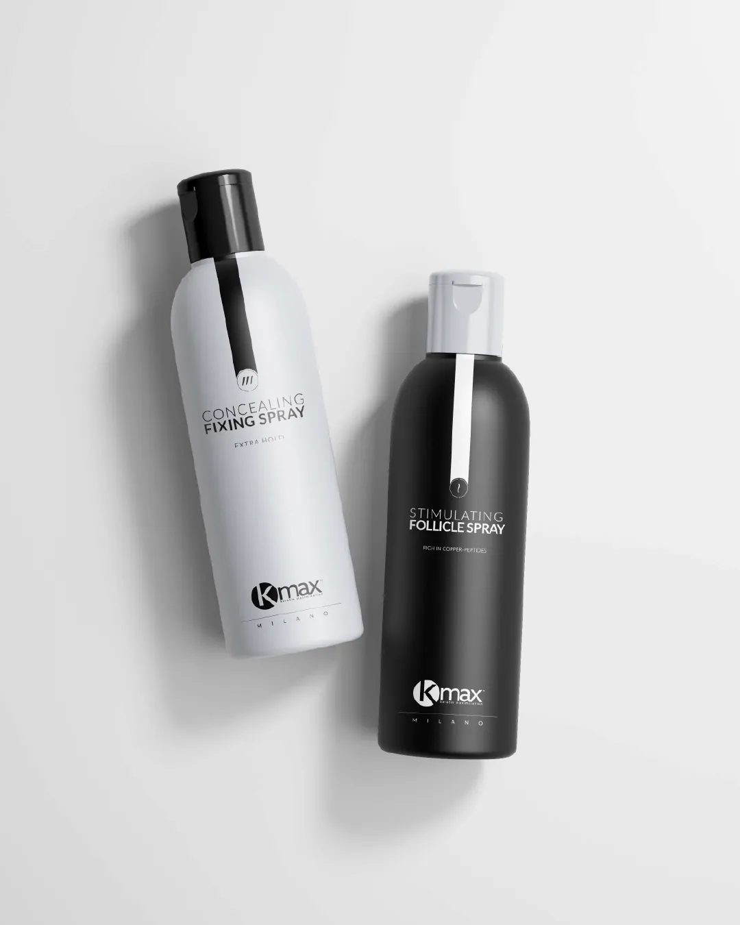 Deux flacons spray vus du dessus : Concealing Fixing Spray, blanc à bouchon noir et bande noire, et Stimulating Follicle Spray, noir à bouchon gris